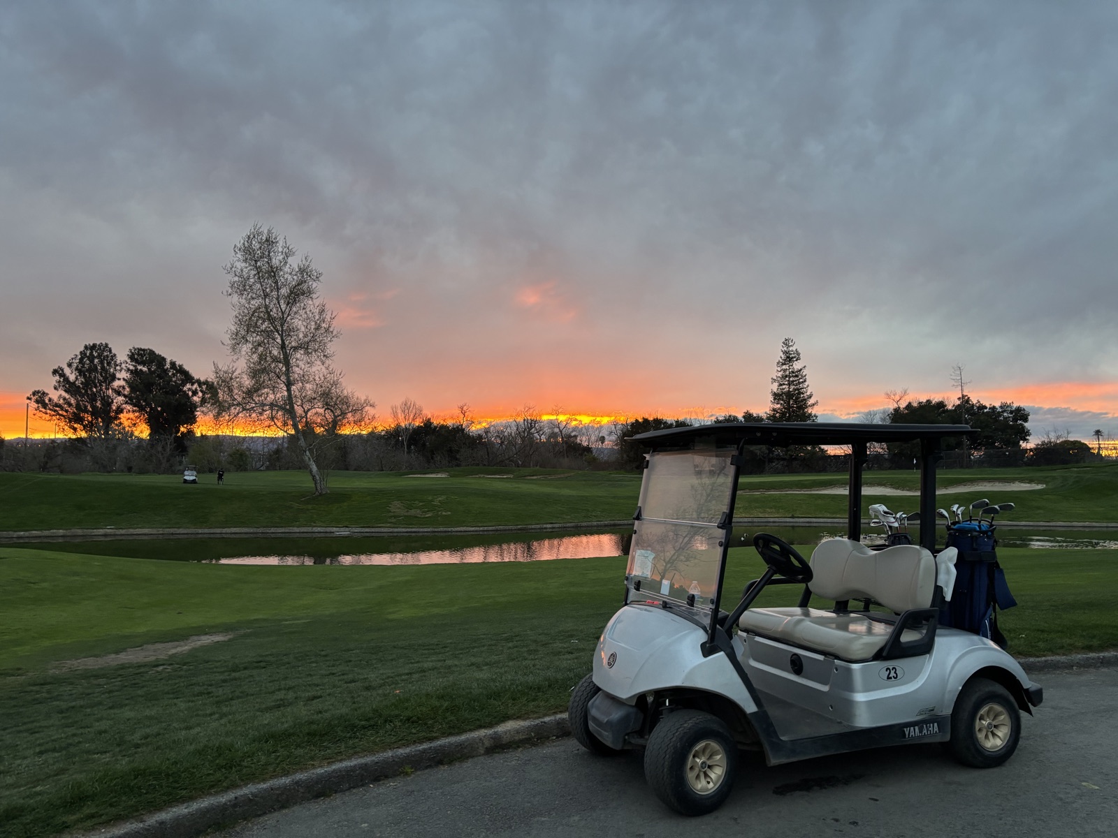 Golf cart by the pond under a burning sunset